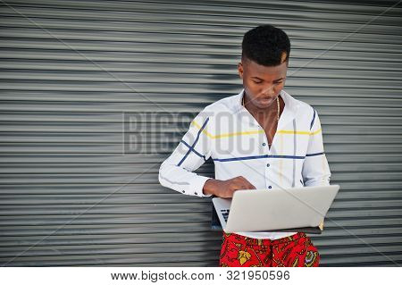 Portrait Of Handsome Stylish African American Model Man In Red Throusers And White Shirt With Laptop