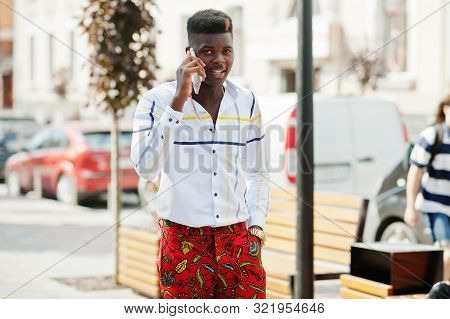 Portrait Of Handsome Stylish African American Model Man In Red Throusers And White Shirt With Cell P