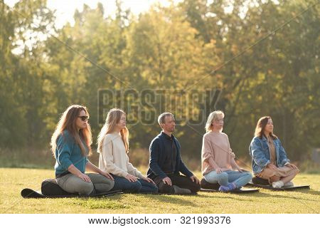 Group Of Young Sporty People Practicing Yoga Lesson With Instructor, Sitting In Padmasana Exercise, 