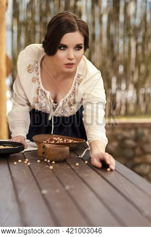 Portrait Of Sexy Brunette Girl In Village Dress Picking Colorful Kidney Beans On Table In Village En