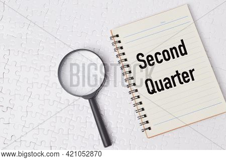 Top View Of Magnifying Glass And Notebook Written With Second Quarter. Business Concept