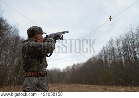 Dusk Was Falling In The Spring Forest. A Woodcock Flies Over A Forest Clearing. The Hunter Shoots Hi