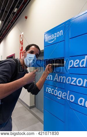 Sabadell, Spain - 30 March 2021 - Young Man Picking Up A Package From A Amazon Locker, Wearing A Blu