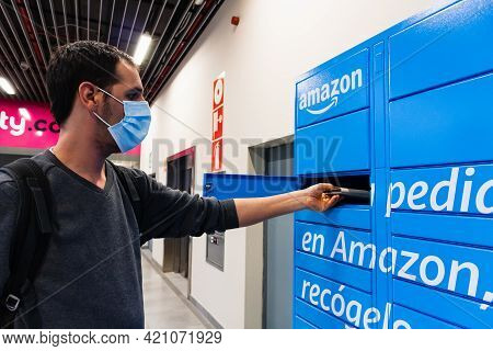 Sabadell, Spain - 30 March 2021 - Young Man Picking Up A Package From A Amazon Locker, Wearing A Blu