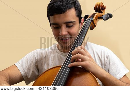 Young Teenage Girl Smiling And Playing Fretted String Musical Instrument Cello Placing Notes With Le