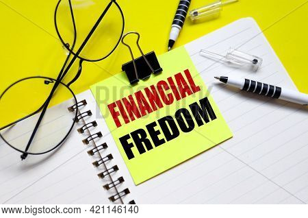 Financial Fredom. Text On Bright Yellow Sticker. On The Blanket. Yellow Background And Black Glasses