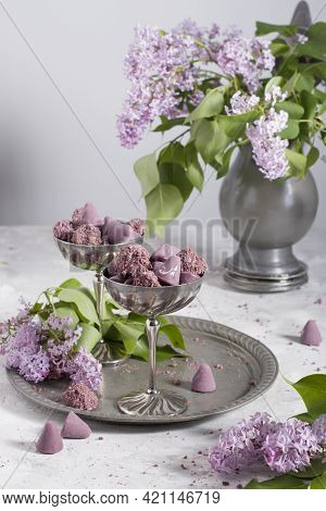 Belgian Sweets Cuberdon And Pralines In Silver Glasses, Spring Still Life With Lilac Flowers