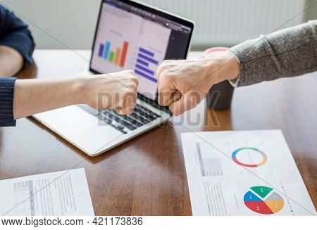 Close Up Of Young Businessman And Businesswoman Making The Fist Bump On Building Background. Busines