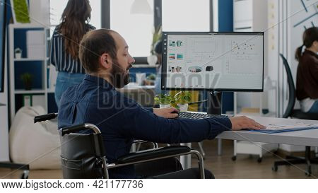 Immobilized Paralysed Handicapped Manager Analysing Graphs And Typing On Computer Sitting In Wheelch