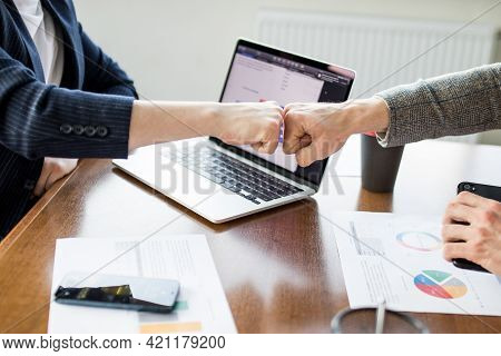 Close Up Of Young Businessman And Businesswoman Making The Fist Bump On Building Background. Busines
