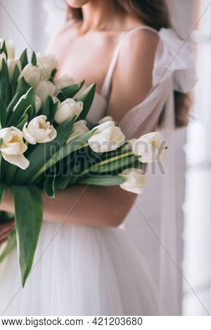 Wedding Bouquet Of White Tulips In The Hands Of A Beautiful Bride Indoor. Selective Focus
