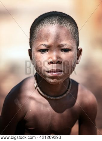 OPUWO, OTJIWARONGO REGION  NAMIBIA - MAY 4, 2021: Young unidentified Himba boy with the typical necklace in Himba living museum during a appearance in front of tourists