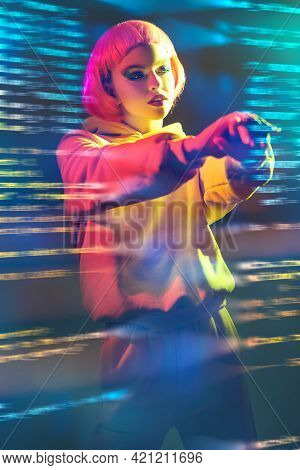 Youth fashion and beauty trends.  Modern girl with bright pink hair and glitter makeup poses in yellow suit in mixed color light. Sport chic fashion. 