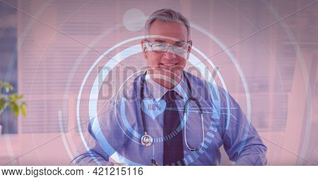 Heart rate monitor against portrait of caucasian senior male doctor smiling at hospital. medical research and technology concept