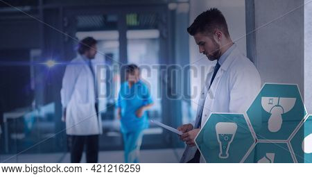 Spot of light and multiple medical icons against male doctor using digital tablet at hospital. healthcare and medical professionalism concept