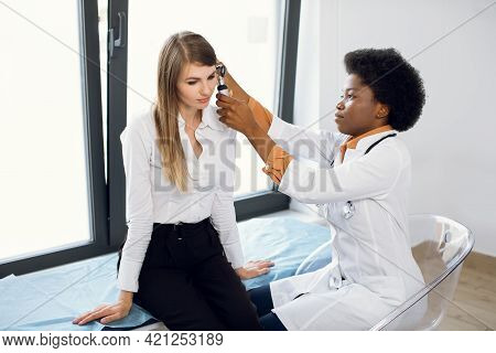 Young Attractive Caucasian Woman Getting Medical Ear Exam At Modern Clinic. Female Afro Ent Practiti