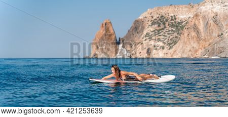 Sporty Girl On A Glanders Surfboard In The Sea On A Sunny Summer Day. In A Striped Swimsuit, Lying O