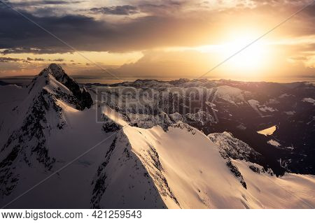 Aerial View From Airplane Of Blue Snow Covered Canadian Mountain Landscape In Winter. Colorful Orang