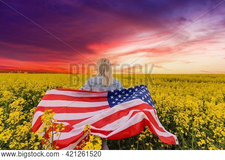 Adult Woman Holding American Flag With Pole, Stars And Stripe In A Yellow Rapeseed Field. Usa Flag F