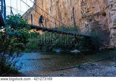 A Young Girl Crossing The Wooden Suspension Bridges. Ruta De Los Pantaneros In The Town Of Chulilla 
