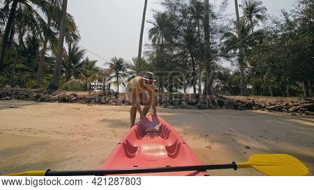 Man With Sunglasses And Hat Rows Pink Plastic Canoe Along Sea Against Green Hilly Islands With Wild 