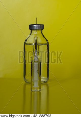 Syringe And Amul On A Yellow Background In An Unusual Perspective