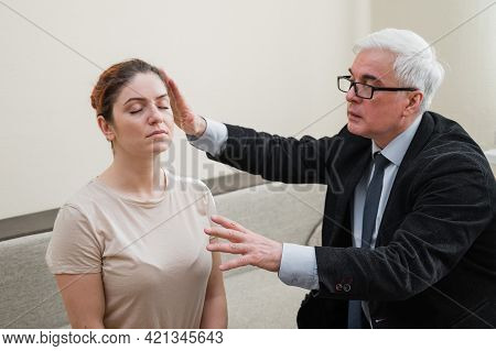 Mature Gray-haired Man Hypnotizes Caucasian Woman During Hypnotherapy Session. The Psychologist Uses