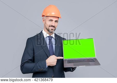 Happy Man In Hard Hat Pointing Finger On Laptop Green Screen For Copy Space, Presenting Product.