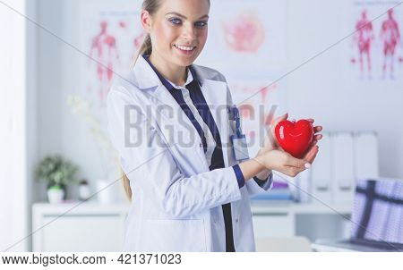 A doctor with stethoscope examining red heart, isolated on white background