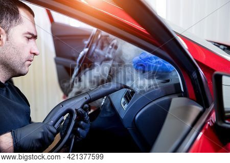 Car Service Worker Cleans Interiror With Steam Cleaner