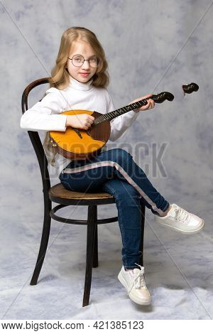 Cute Little Girl Learning To Play The Plucked Musical Instrument, Domra.