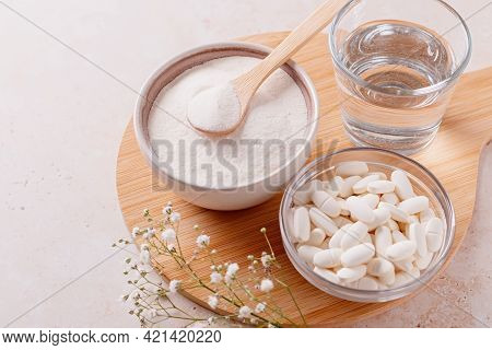 Collagen Powder, Pills And Glass Of Water On Wooden Tray, Top View