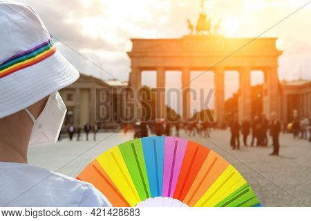 Mature Caucasian Lgbt Woman In Berlin With Rainbow Fan And Ribbon On White Summer Hat. Rainbow, Symb