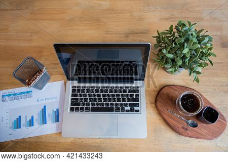 Office Laptop Business Financial Document Chart And Graph On Wooden Table With Coffee Cup. Flat Lay 