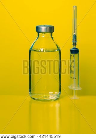 Syringe With A Needle And Medicine In A Bottle On A Yellow Background