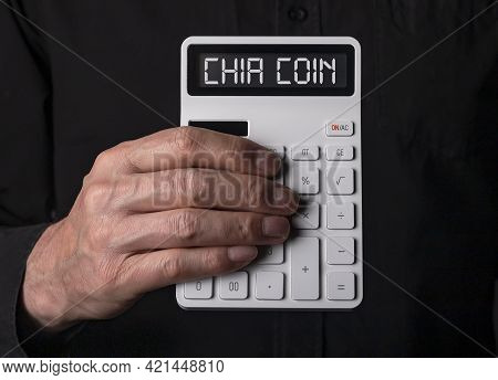 Chia Coin Concept. Hiacoin Word On Calculator In Male Hand Over Black Background. Crypto Investing.