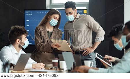 Colleagues Having Meeting In Boardroom, Woman Showing Documenation
