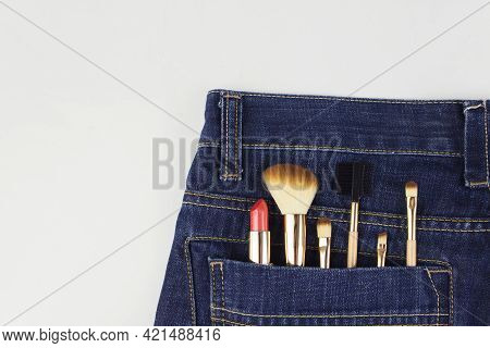Cosmetics Out Of The Pocket Of Jeans. Makeup Objects In Jeans Pocket On Grey Background. Concept Of 