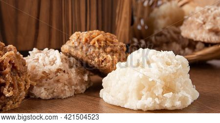 Cocada, Coconut Candy From Brazil, White And Brown Cocadas Fallen From A Straw Basket On Wooden Surf