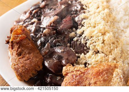 Brazilian Feijoada, White Dish With A Delicious Brazilian Feijoada, Rice, Farofa, And Fried Pork Wit