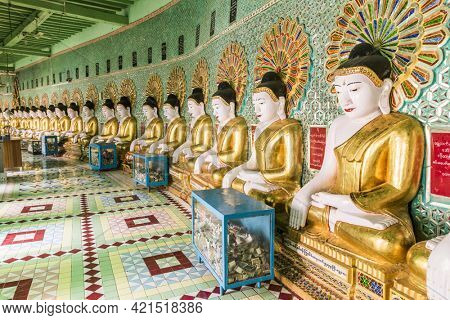 SAGAING, MYANMAR - JANUARY 30, 2016: Row of golden Buddha statues and offering boxes inside U Min Thonze Sel Pagoda located on Sagaing Hill. Mandalay Region, Myanmar