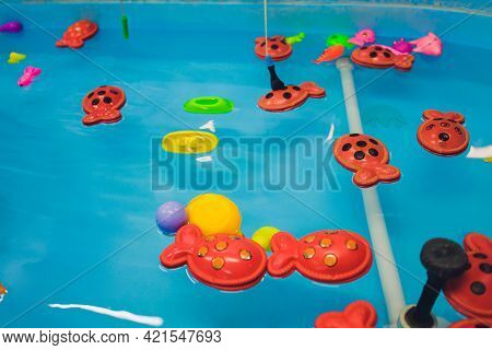 Fishing In The Paddling Pool. Childrens Toys In The Pool. Toy Fish Fishing Rod. Cheerful Children Fi