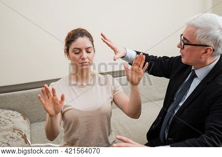 Mature Gray-haired Man Hypnotizes Caucasian Woman During Hypnotherapy Session. The Psychologist Uses