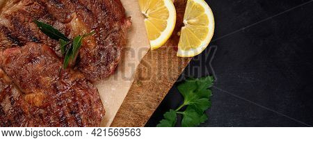 Delicious Prepared Meat Steaks With Seasoning And Herbs On Dark Background.