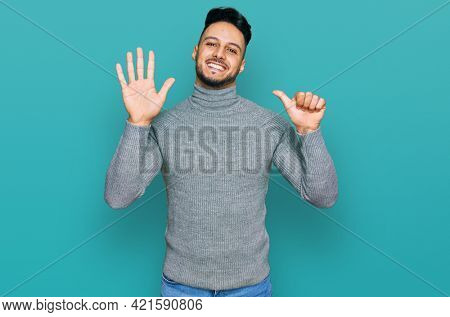 Young arab man wearing casual clothes showing and pointing up with fingers number six while smiling confident and happy. 