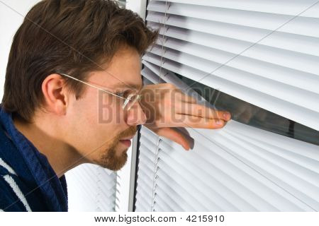 Jovem em roupão, olhando para fora da janela