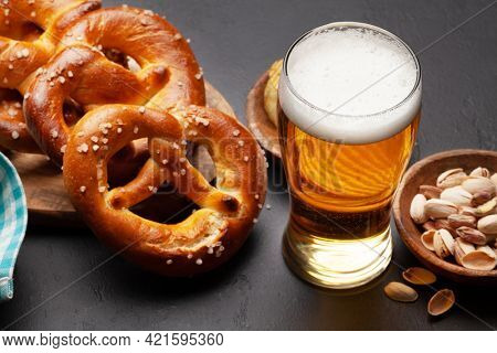 Lager beer mug, nuts, potato chips and fresh baked homemade pretzel with sea salt on stone table. Classic beer snack