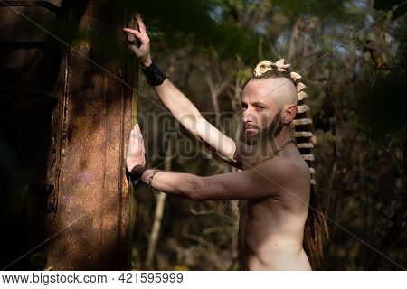 Strong Sexy Young Man With Fangs Necklace And Bone Jewelry In The Dreads Hair, As A Symbol For Back 