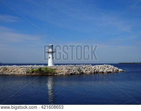 White Washed Lighthouse Looks Over The Deep Blue Ocean.