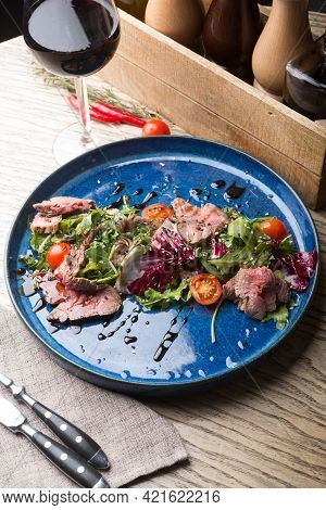 Roastbeef Salad Served With Glass Of Red Wine In A Bar